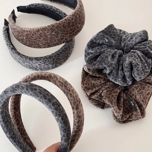 Détail de serre-têtes et chouchous léopard en velours dans les tons brun et gris