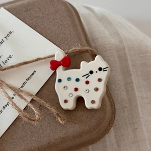 Détail de la pince à cheveux chat en acétate blanc avec strass colorés et nœud rouge vif