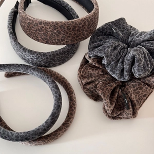 Détail de serre-têtes et chouchous léopard en velours dans les tons brun et gris