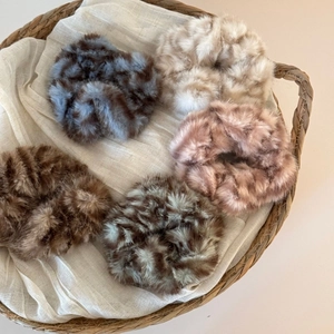 Gros plan détaillé de 5 chouchous en peluche aux couleurs variées dans un panier tressé