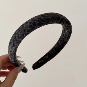 Détail du serre-tête en velours léopard gris foncé avec logo intérieur doré