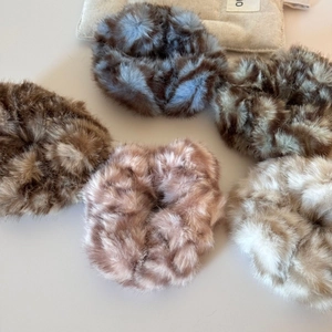 Cinq chouchous en peluche duveteuse aux couleurs d'automne sur fond beige naturel