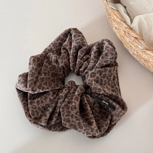 Gros plan du chouchou en velours avec motif léopard et étiquette de marque