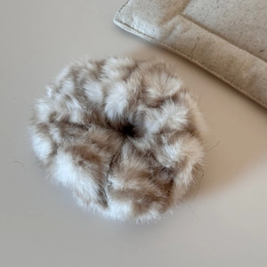 Détail d'un chouchou en peluche imprimé léopard avec une texture douce en fausse fourrure