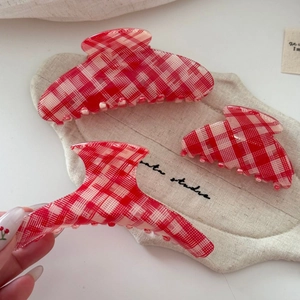 Detailed view of red and white checkered acetate hair claw clips in three sizes