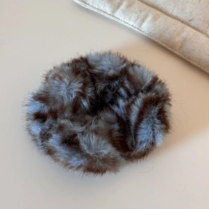Détail d'un chouchou en fausse fourrure pelucheuse avec motif léopard marron et bleu