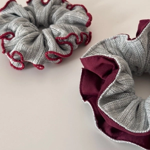Detail of two-piece grey knitted scrunchies with burgundy ruffled edges for winter hair styling