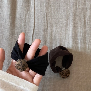 Detail view of velvet scrunchies with leopard print beads in black and dark brown
