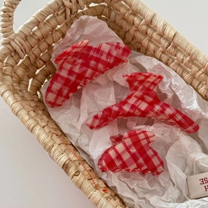 Red and white checkered acetate hair claw clips set in a rustic woven basket setup
