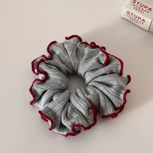 Detail of grey knitted scrunchie with red scalloped edges and soft ribbed texture