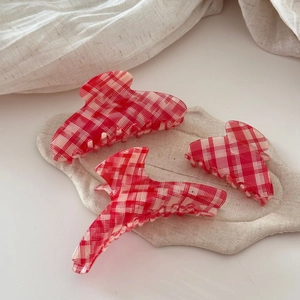 Detailed view of red and white checkered acetate hair claws in various sizes and shapes