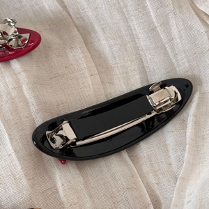 Detail view of the silver metal spring clip mechanism on the black acetate hair bow
