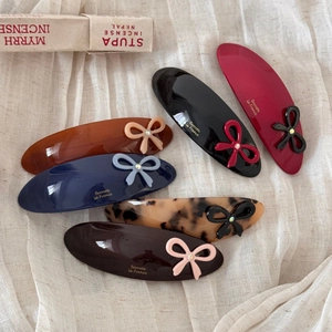 Detail view of colorful acetate oval hair clips with delicate bows and rhinestones