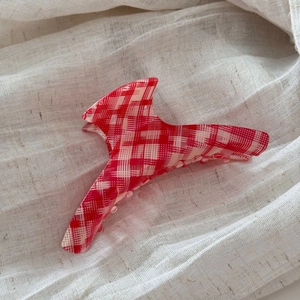 Detail view of the red and white checkered acetate hair claw clip with glossy finish