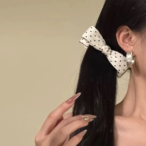 Polka dot bow banana clip for thick hair shown on a model from a side rear view angle