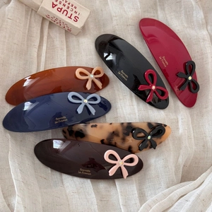 Acetate bow hair clip set in six colors with sparkling diamond accents and golden branding