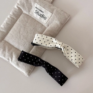 Detail view of large polka dot bow hair clips in black and white fabric texture