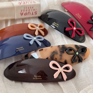 Elegant acetate bow hair clips with rhinestones in six colors on linen background