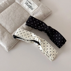 Detailed view of polka dot bow banana hair clips in black and white fabric finish