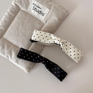 Detailed view of black and beige polka dot bow hair clips with durable metal banana grip