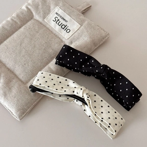 Detailed view of large black and white polka dot bow banana clips on a quilted surface