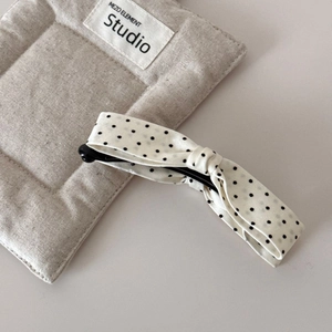 Detailed view of the polka dot fabric bow banana clip on a textured linen background