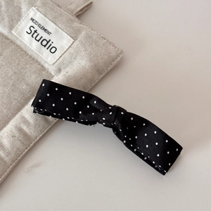 Detailed close-up of large black bow banana clip with white polka dots for thick hair
