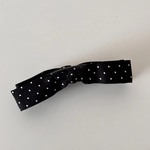 Close-up of black satin bow hair clip with white polka dots and metal banana clip