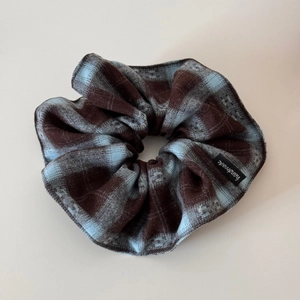 Détail d'un chouchou en tissu à carreaux marron et bleu avec étiquette Handmade noire