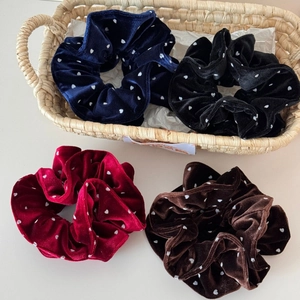 Detailed close-up of four velvet polka dot hair scrunchies in classic autumn colors