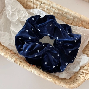 Detail of navy blue velvet polka dot scrunchie with soft texture in a woven basket