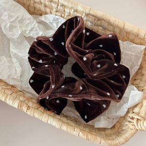 Detailed shot of dark brown velvet scrunchie with white heart patterns in a basket
