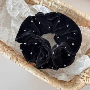 Detail of black velvet scrunchie with white heart pattern in a straw basket