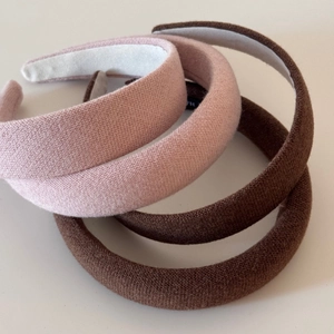 Close-up of three knitted sponge headbands in pink and brown with anti-slip lining