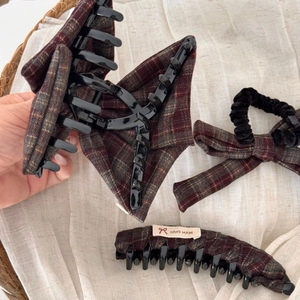 Close-up of vintage plaid bow hair clips and velvet scrunchie set on beige fabric