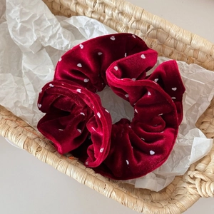 Detail of red velvet oversized scrunchie with heart pattern in a woven basket
