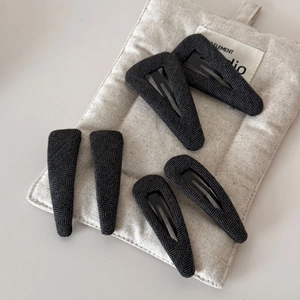 Détail de 6 barrettes grises en tissu à chevrons sur un sac matelassé beige doux