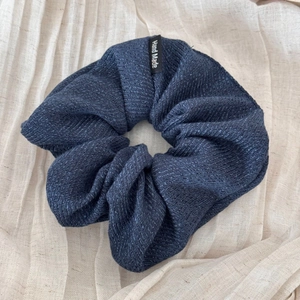 Detailed view of large navy blue striped fabric scrunchie with a Hand Made woven label