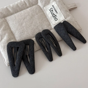 Détail de six barrettes à cheveux grises à chevrons sur un sac de présentation