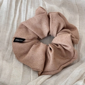 Detail of a large pink striped fabric scrunchie with a Hand Made label on cotton linen
