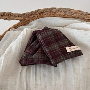 Detail of red plaid fabric hair claw with hand made label on linen background