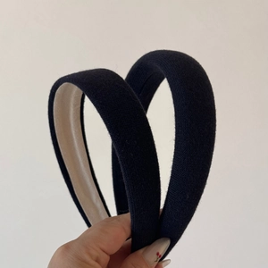 Detail showing two thick padded headbands in black knit fabric and contrast beige lining