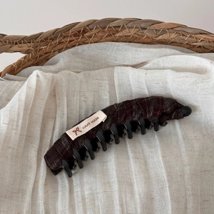 Detail of handmade plaid bow hair clip with fabric label on natural linen background