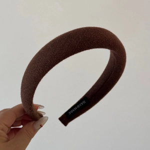 Detail of dark brown padded sponge headband showing handmade tag and knit texture