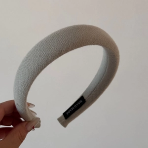 Detailed shot of handmade grey knitted sponge headband with woven texture and inner label