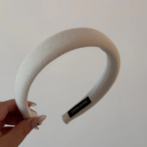 Detail of cream knitted padded headband with a handmade label and soft thick texture