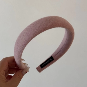 Detailed view of pink knitted sponge headband with handmade label and soft texture