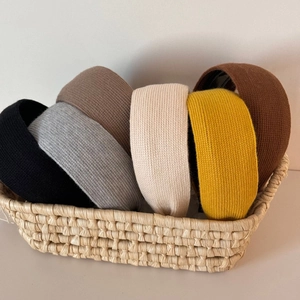 Close-up of six assorted knit headbands in a woven basket showing ribbed textures