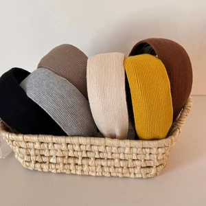 Close-up of thick knitted headbands in multiple colors neatly placed in a woven basket