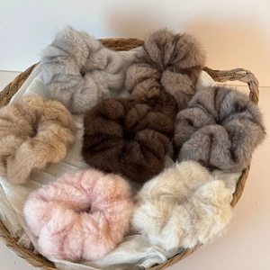 Set of 7 plush faux mink fur scrunchies in neutral colors displayed in a basket